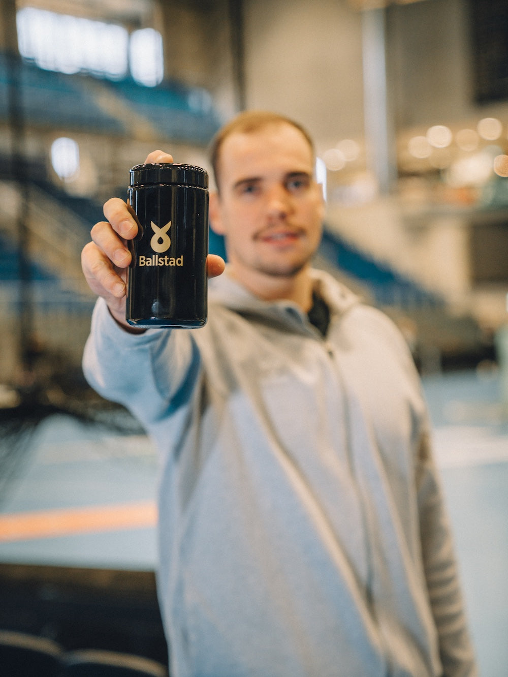 unger Mann hält ein Ballstad-Nahrungsergänzungsmittel in die Kamera – hochwertiges Omega-3-Produkt zur Unterstützung von Gesundheit, Sport und geistiger Leistungsfähigkeit